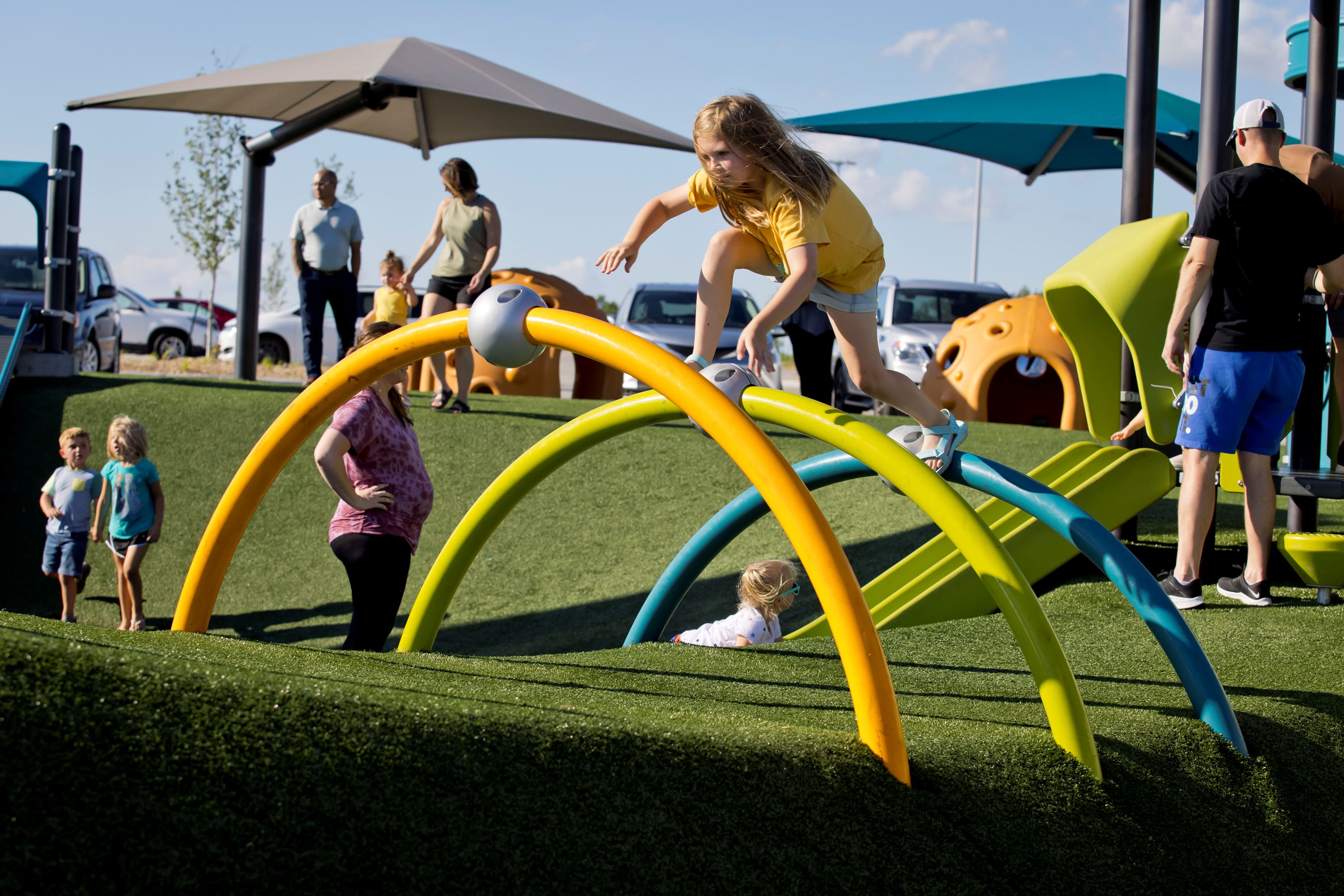 A young girl climbs across the tops of large half hoops stuck into the turf